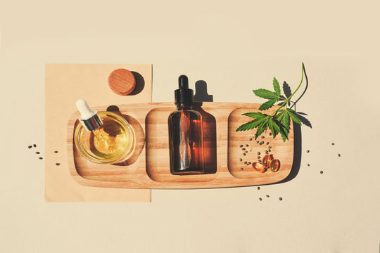 CBD oil, CBD tincture, and a hemp leaf beautifully arranged on a wooden board