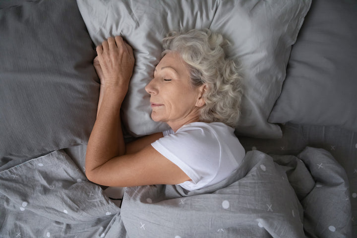 A gray haired woman sleeping comfortably on her side