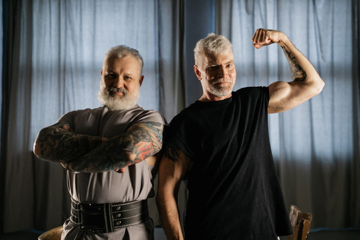 Two older men crossing their arms and flexing their muscles