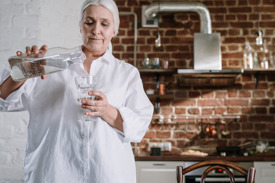 A woman in a white lab coat pouring water into a glass