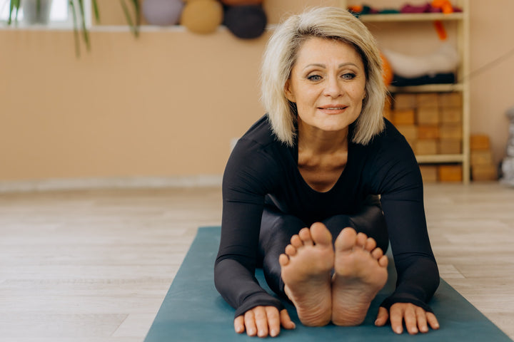 A woman with her legs outstretched on a yoga mat