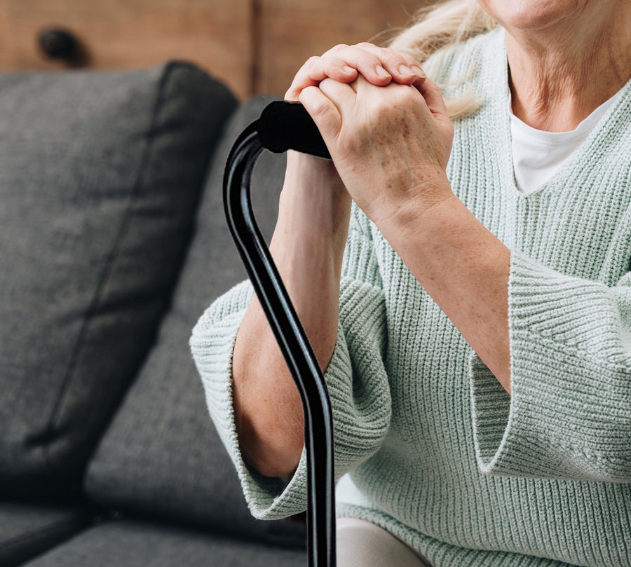 Woman's hands comfortably holding onto the handle of a black cane.