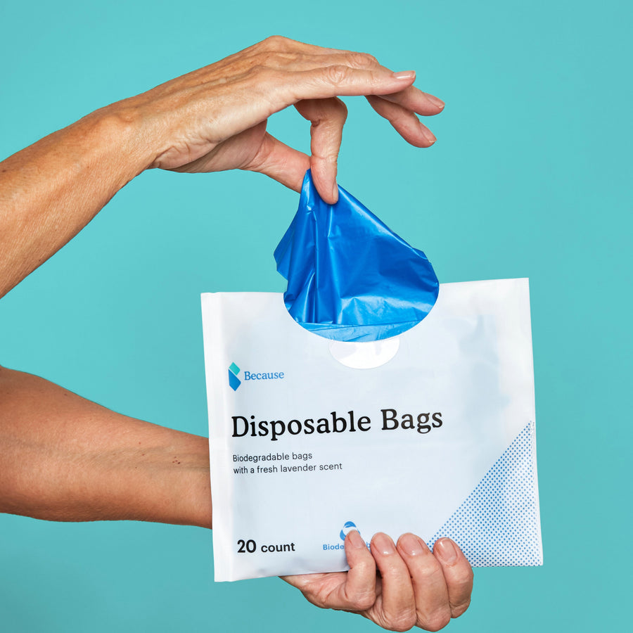 Disposable bags with opening at the top with a woman's hand pulling one out of the top of the bag.
